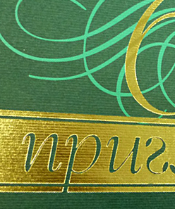 Тиснение золотой фольгой на зеленой дизайнерской бумаге.